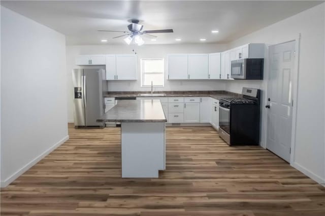 kitchen featuring appliances with stainless steel finishes, a kitchen island, sink, dark hardwood / wood-style floors, and white cabinetry