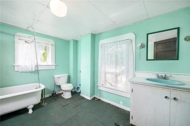 bathroom featuring a drop ceiling, toilet, a tub, and vanity