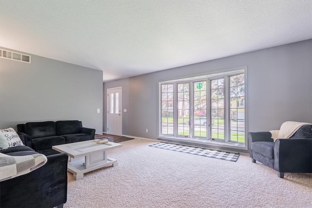 carpeted living room with baseboards, a textured ceiling, and visible vents