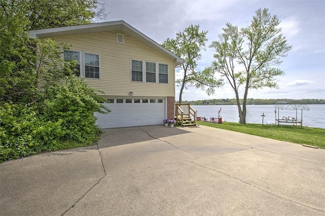 view of property exterior with a garage, a water view, and concrete driveway
