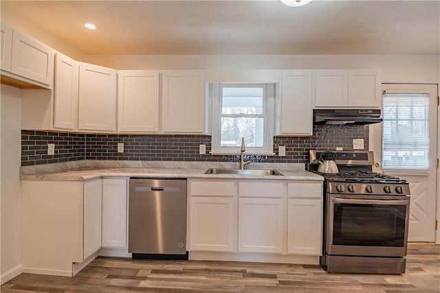 kitchen with white cabinets, stainless steel appliances, extractor fan, and sink