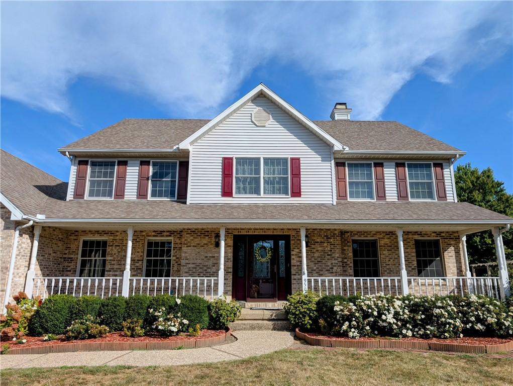 colonial-style house featuring a porch and a front yard