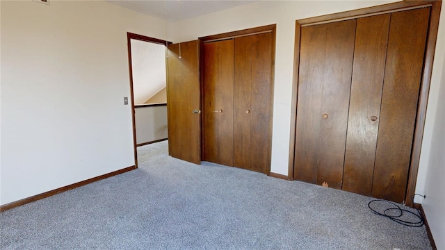 unfurnished bedroom with carpet flooring, two closets, and baseboards