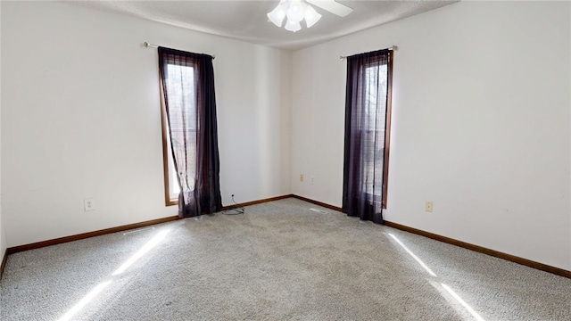 empty room with light colored carpet, baseboards, and ceiling fan