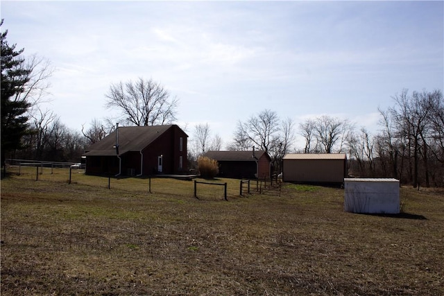 view of yard featuring an outbuilding, an outdoor structure, and fence