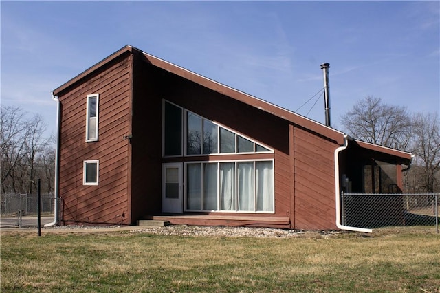 back of property with a lawn and fence