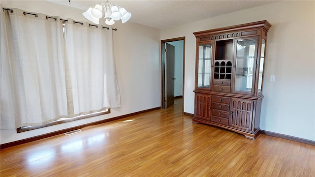 unfurnished dining area featuring a notable chandelier, visible vents, light wood-style flooring, and baseboards