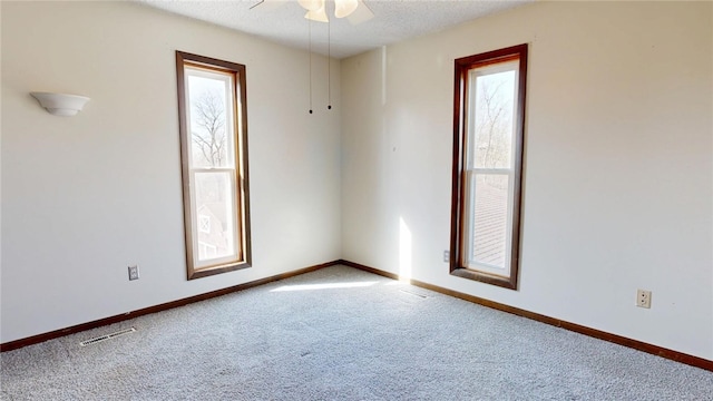 carpeted spare room with visible vents, baseboards, a textured ceiling, and a ceiling fan