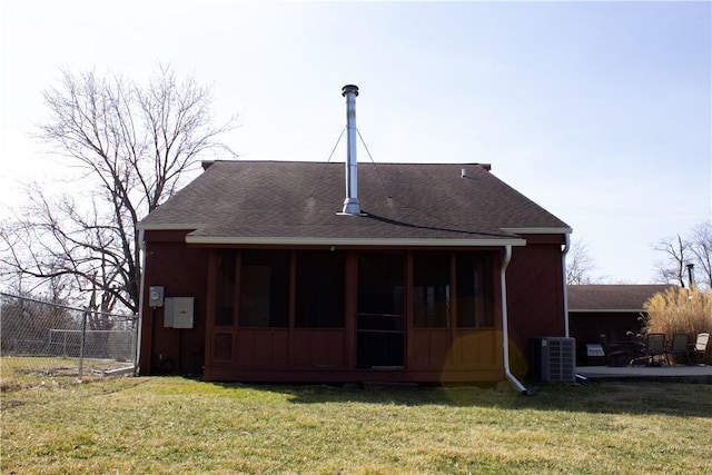 rear view of property featuring a lawn, cooling unit, roof with shingles, and a sunroom