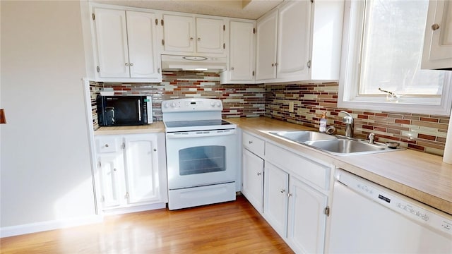 kitchen with under cabinet range hood, decorative backsplash, white appliances, white cabinetry, and a sink