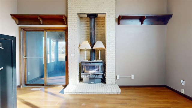 interior details with baseboards, wood finished floors, and a wood stove