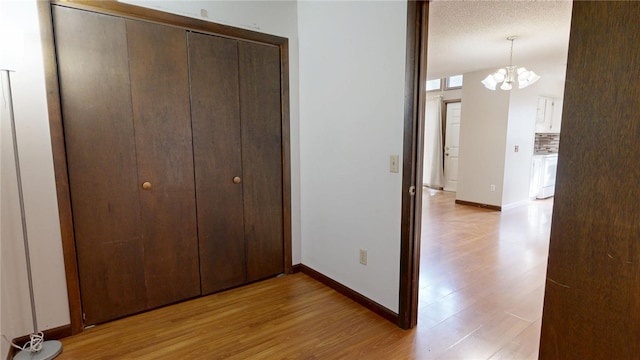 interior space featuring baseboards, light wood-type flooring, a closet, and a textured ceiling