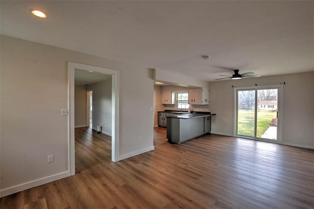 kitchen with ceiling fan, kitchen peninsula, dark hardwood / wood-style floors, and white cabinets