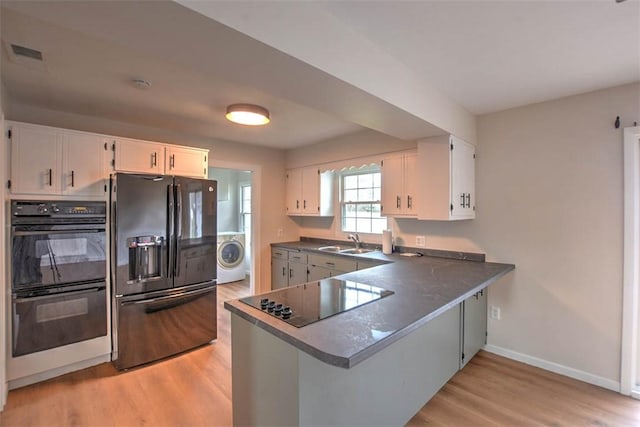 kitchen with washer / clothes dryer, white cabinetry, black appliances, sink, and kitchen peninsula