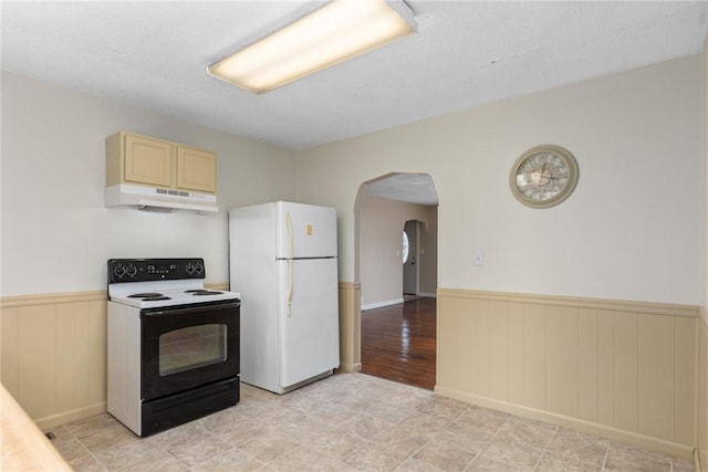 911 Saint Anthony Ave, Effingham, IL 62401 - kitchen with range with electric stovetop, freestanding refrigerator, a wainscoted wall, under cabinet range hood, and arched walkways