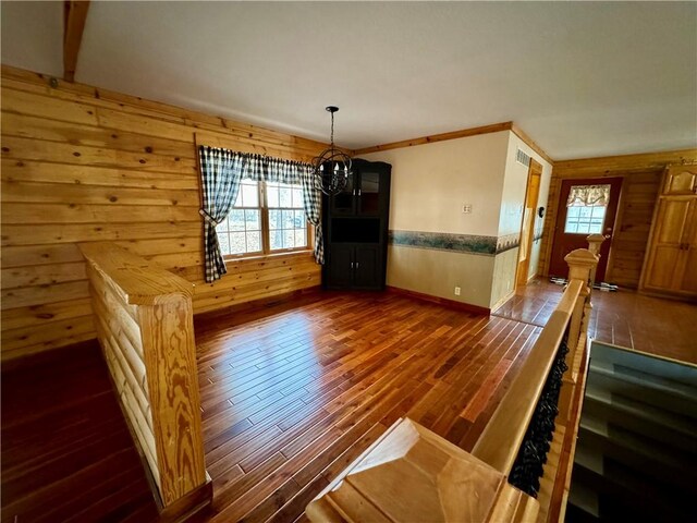 unfurnished dining area with ornamental molding, a chandelier, and dark hardwood / wood-style floors