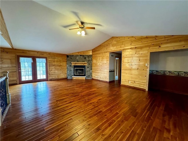 unfurnished living room with ceiling fan, dark wood-type flooring, wooden walls, and lofted ceiling