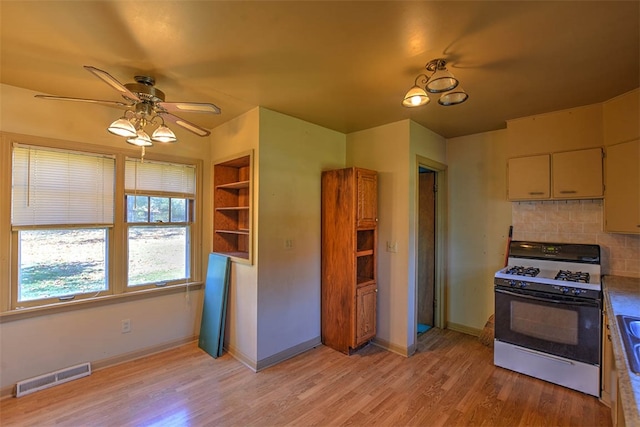 kitchen with backsplash, light hardwood / wood-style floors, built in features, and white range with gas cooktop