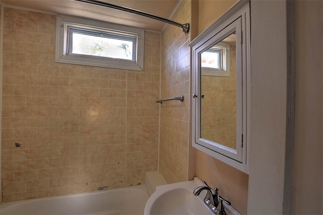 bathroom with sink, a healthy amount of sunlight, and tiled shower / bath