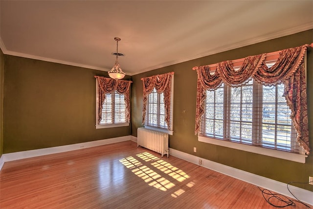 unfurnished dining area featuring hardwood / wood-style floors, ornamental molding, and radiator