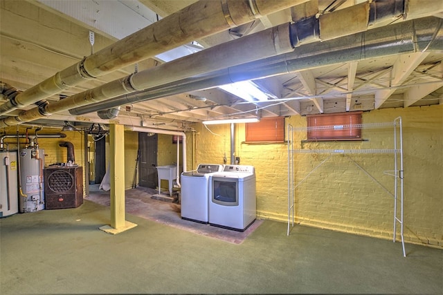 basement featuring brick wall, separate washer and dryer, and water heater