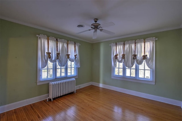 spare room featuring plenty of natural light, wood-type flooring, radiator heating unit, and ornamental molding