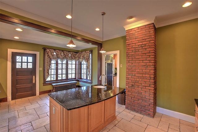 kitchen with sink, an island with sink, dark stone counters, decorative light fixtures, and ornamental molding