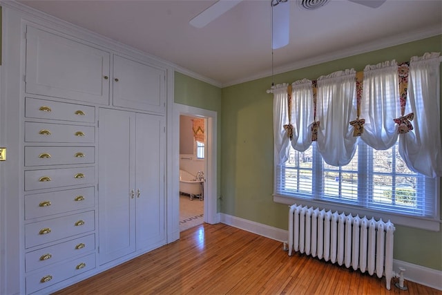 bedroom with ensuite bath, radiator heating unit, light hardwood / wood-style floors, and ornamental molding