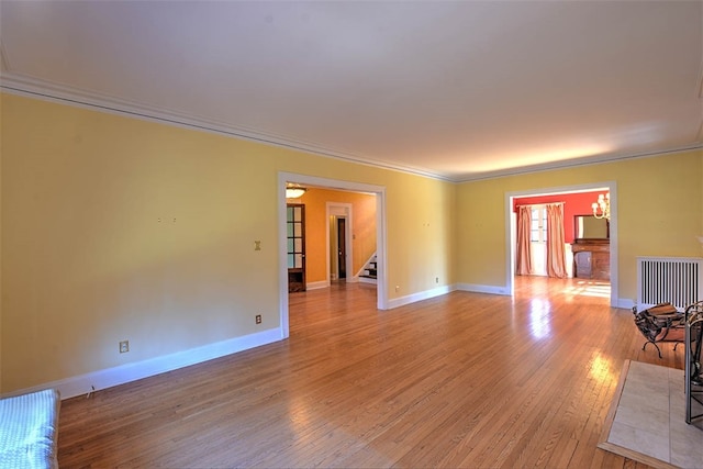 empty room with light hardwood / wood-style floors, ornamental molding, and radiator heating unit