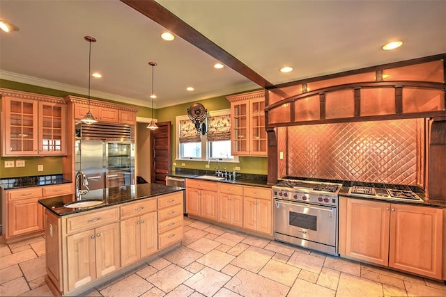 kitchen with sink, tasteful backsplash, decorative light fixtures, high quality appliances, and a center island with sink