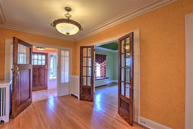 entryway featuring light hardwood / wood-style floors, crown molding, and french doors