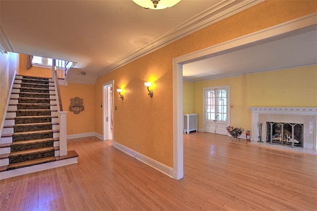 unfurnished living room featuring radiator heating unit, a fireplace, ornamental molding, and hardwood / wood-style flooring