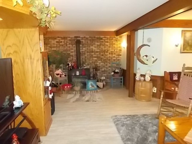 interior space featuring beam ceiling, light hardwood / wood-style floors, and a wood stove