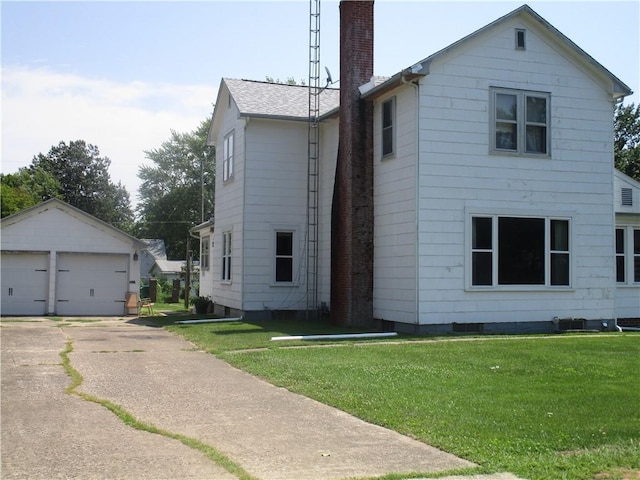 506 W 5th St, Pana, IL 62557 - view of front facade featuring a chimney, an outbuilding, a garage, and a front lawn
