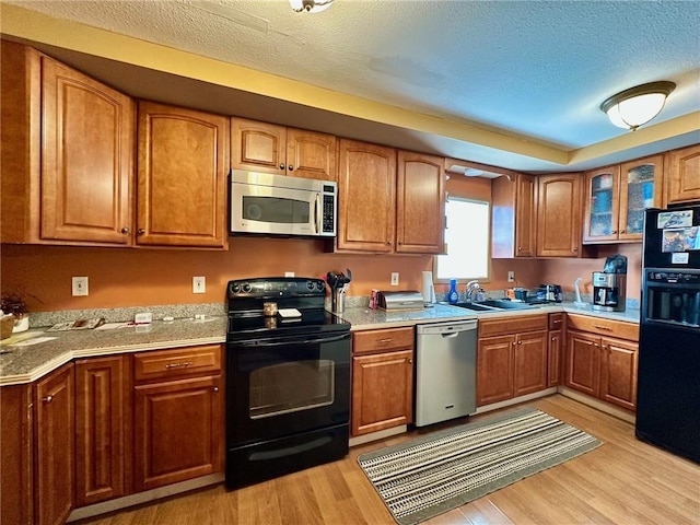 1220 Dewitt Ave, Mattoon, IL 61938 - kitchen featuring black appliances, a sink, brown cabinets, light wood finished floors, and light countertops