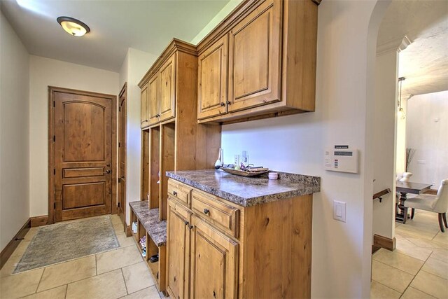 2125 Reserve Way, Decatur, IL 62521 - kitchen with dark countertops, brown cabinetry, arched walkways, light tile patterned floors, and baseboards