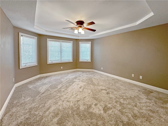 carpeted empty room featuring ceiling fan, a raised ceiling, and a textured ceiling