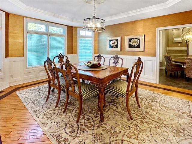 dining room featuring a chandelier, a raised ceiling, light hardwood / wood-style flooring, and ornamental molding