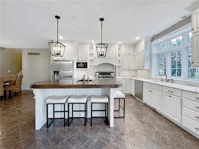 kitchen featuring white cabinetry, a kitchen island, hanging light fixtures, and appliances with stainless steel finishes