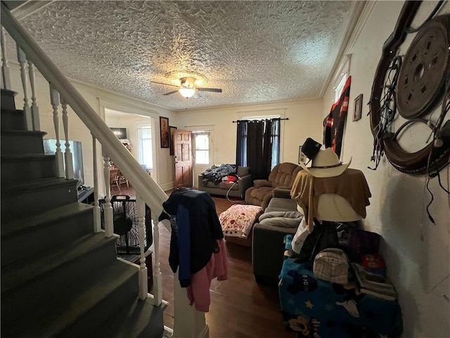 living area featuring a textured ceiling, a ceiling fan, stairs, and wood finished floors