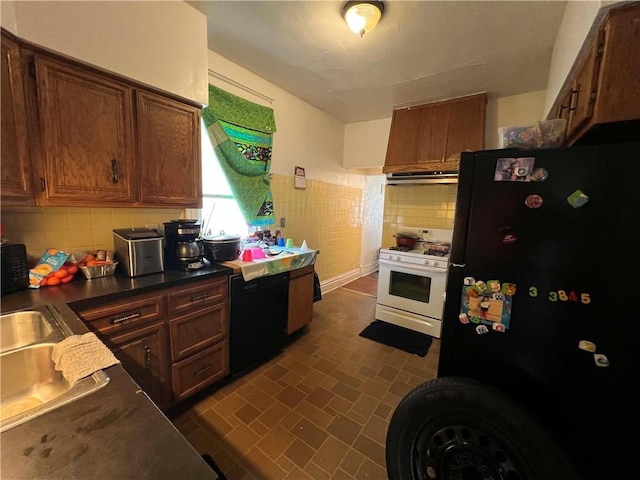 kitchen with dark countertops, tasteful backsplash, black appliances, brick patterned floor, and under cabinet range hood