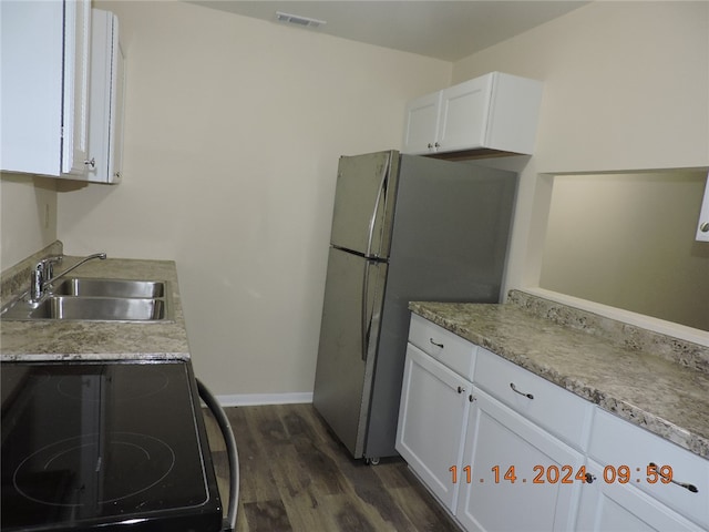 kitchen with black stove, sink, dark hardwood / wood-style floors, stainless steel fridge, and white cabinets