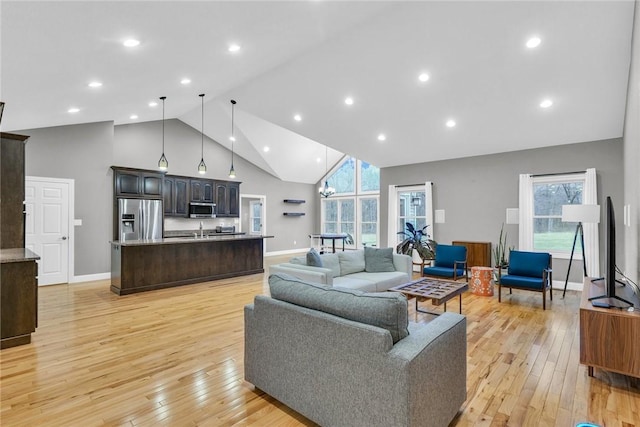 living room with high vaulted ceiling, light hardwood / wood-style floors, and sink