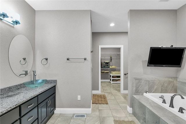 bathroom with vanity, tiled bath, and tile patterned flooring