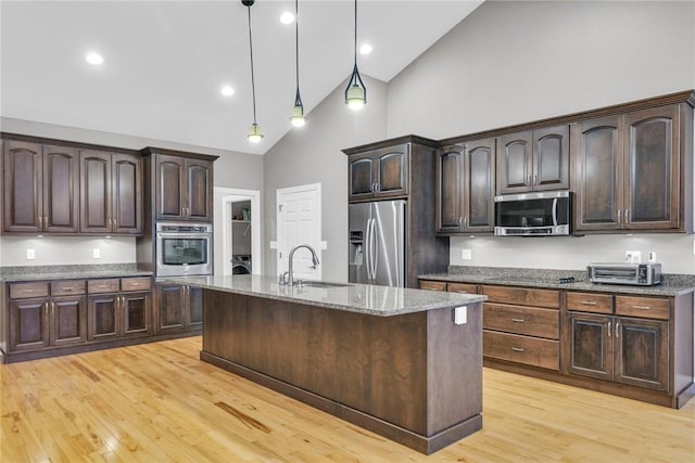 kitchen featuring stainless steel appliances, hanging light fixtures, sink, and dark brown cabinetry