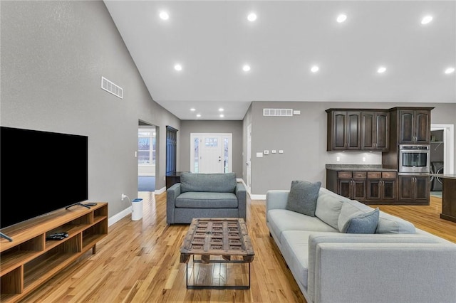 living room featuring high vaulted ceiling and light wood-type flooring