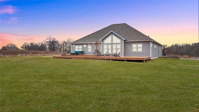 back house at dusk featuring a yard and a deck