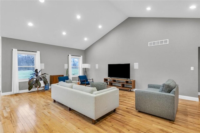 living room featuring high vaulted ceiling and light wood-type flooring