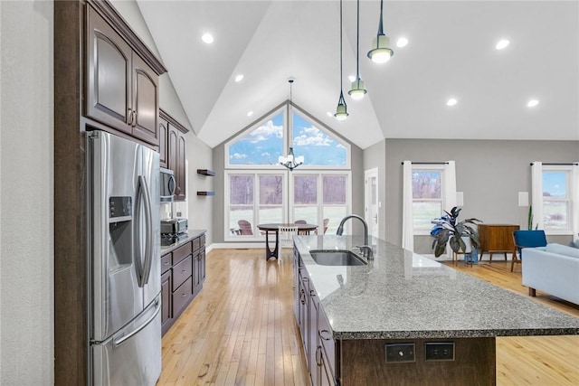 kitchen featuring sink, stainless steel fridge with ice dispenser, dark brown cabinets, a center island with sink, and light wood-type flooring