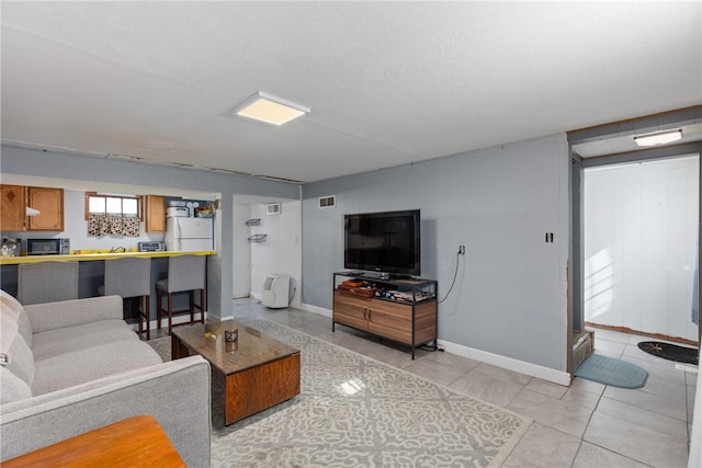 living room with a textured ceiling and light tile patterned flooring